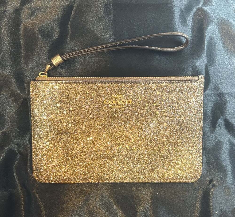 Coach Metallic gold glitter with silver stars throughout the wristlet clutch.